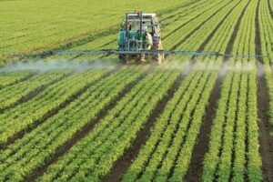 a very green farm with a piece of farming equipment